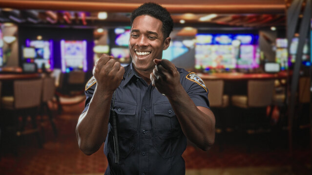 Man in police uniform with badge visible, fists raised and clenched hands in a casino building while miming punches and counting; duty pride.