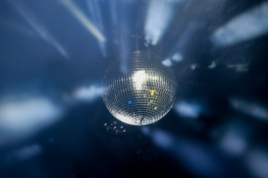 Sparkling disco ball reflecting bright lights in a dark nightclub or party venue with dynamic motion blur effect.