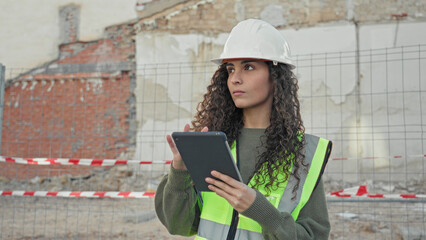 Woman architect holding tablet and tapping screen while wearing hardhat and reflective vest at a building site  determination. © Krakenimages.com