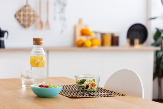 Healthy food pasta salad breakfast on wooden kitchen table with water bottle. Wellness meal prep bowl styled for a morning routine. Healthy breakfast concept.