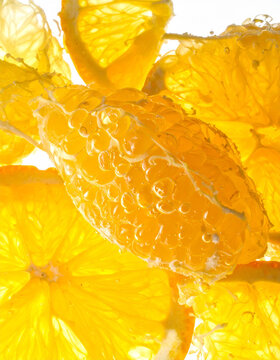 Fresh citrus pulp reveals translucent juice sacs and vibrant yellow segments under a bright kitchen studio light.