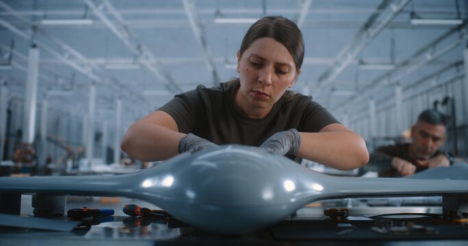 Young Female Worker Assembling Drone Components at Industrial Workbench, Representing Advanced Manufacturing, Aerospace Production, Precision Engineering, Automation, Innovation and Modern Industry.