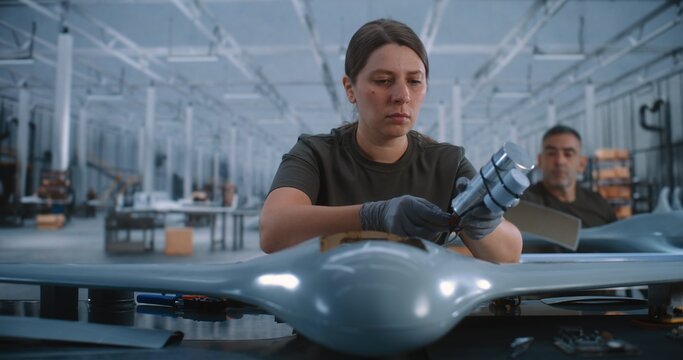 Female Engineer Building Unmanned Aircraft Inside Large Production Facility, Combining Hands on Craftsmanship With Aerospace Technology, Industrial Engineering, Technical Labor and Manufacturing.