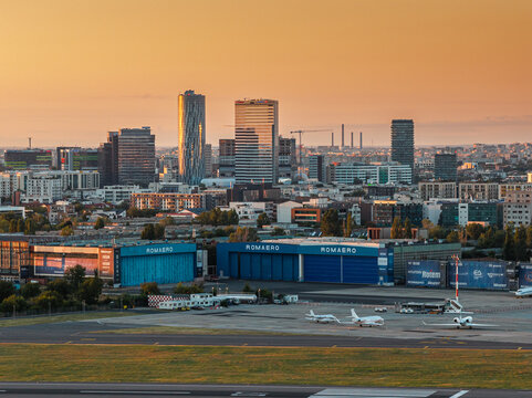 Bucharest, Romania -Sunrise over Baneasa Airport tarmac with Romaero hangars and northern business skyline skyscrapers bathed in golden morning light.