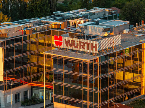 Bucharest, Romania Modern glass facade of Wurth office building in northern Baneasa area illuminated by warm golden sunrise light reflections.
