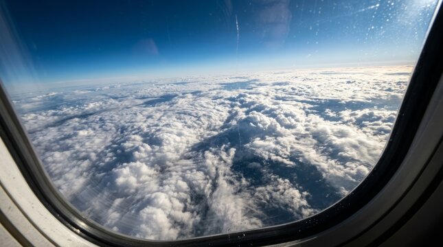 Aerial View of Fluffy White Cumulus Clouds from Airplane Window over Clear Blue Sky Background