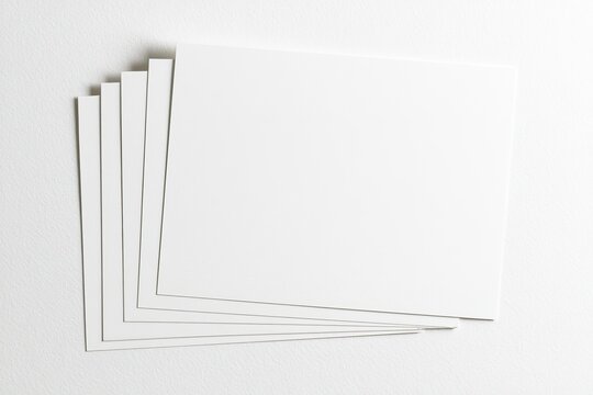 Stack of blank white rectangular cards fanned out on a textured surface