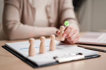 Plakat Human resources recruitment and candidate selection. Woman hand picking chosen wooden figure with check mark over rejected ones.