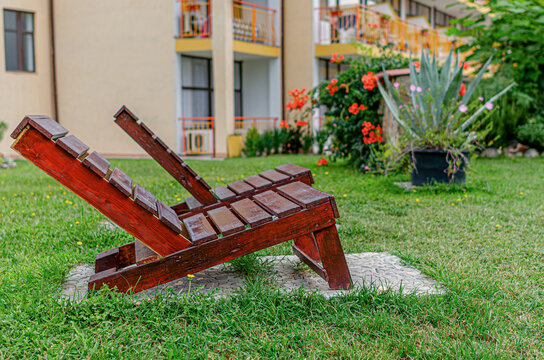 Two wooden sun loungers stand on a green lawn in the garden of a hotel resort.