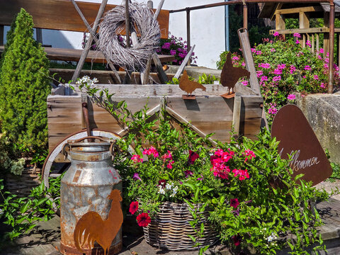 L&auml;ndliche Dekoration im Vintage Stil, alte Milchkanne, Leiterwagen, Blumen