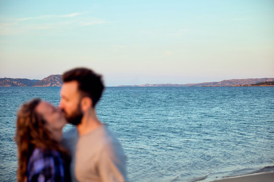 Romantic Couple Kissing on the Beach with Blue Sea and Horizon in Background