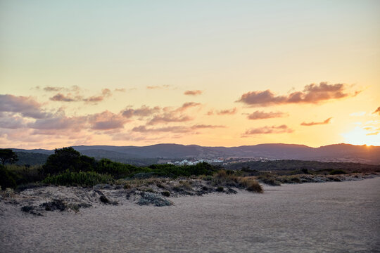 Scenic Sunset Over Coastal Dunes and Distant Hills
