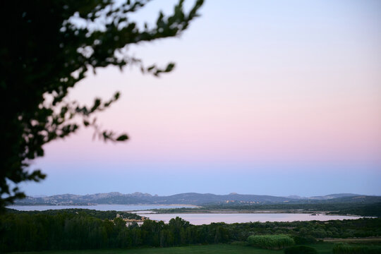 Scenic coastal landscape with distant mountains under a pastel pink twilight sky