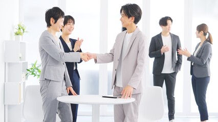明るいオフィスで握手を交わすビジネスマンと同僚の拍手 © folyphoto