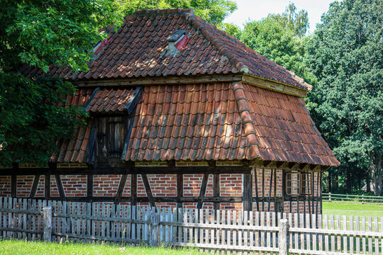 Old timber-framed house with red tiled roof and wooden fence