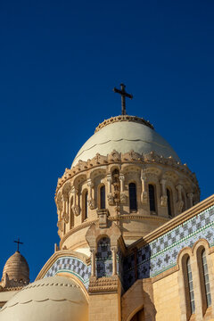 Ornate dome and cross of Notre-Dame d'Afrique basilica against blue sky, North Africa, Algiers, Algeria