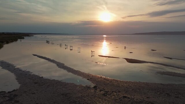 Lake Balaton near Balatonfenyves, Hungary, with receding shoreline, muddy sandy beach and fishing piers during drought on the south coast, panoramic aerial view at sunset.