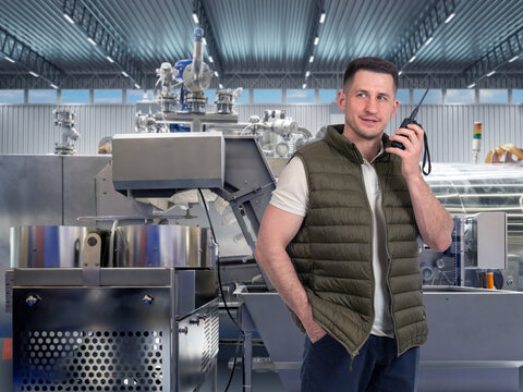 Manufacturing plant. Industrial technician coordinates production equipment by two-way radio while supervising automated machinery and factory operations.