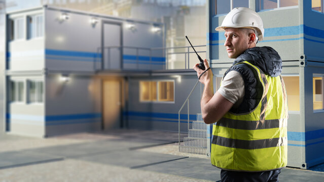 Modular construction. Site supervisor coordinates modular building installation by two-way radio while managing temporary site offices and construction logistics.