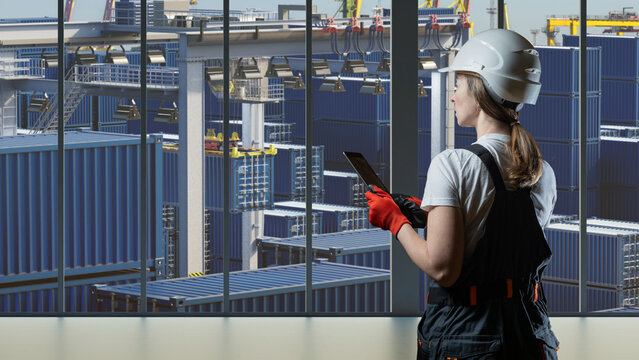 Container terminal. Logistics engineer monitors container storage and cargo handling operations with a tablet at an automated shipping yard.