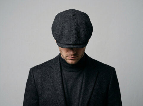 Male model wearing flat cap performing fashion pose in studio with neutral background