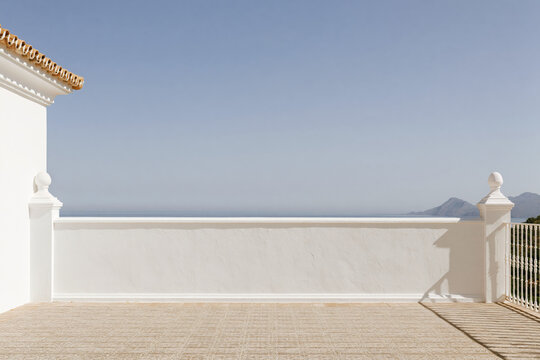 Minimalist Spanish villa terrace wall backdrop with stone finials and a distant sea and mountain view.