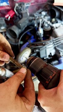 Mechanic uses cordless drill on threaded rod in auto repair garage