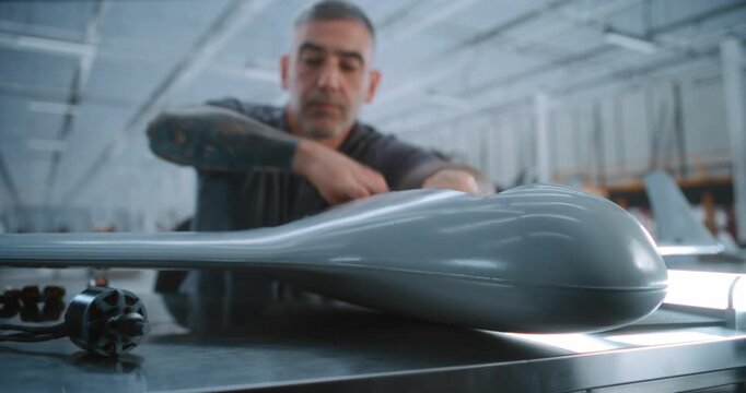 Professional Male Installs Precision Components In Fixed Wing Drone Fuselage, Demonstrating Detailed Aircraft Assembly Work in Large High Technology Production Facility. Advanced Aircraft Assembly.