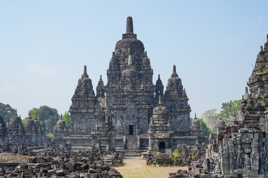 Ancient Sewu Buddhist temple stone ruins with ornate stupas under a clear blue sky in Klaten, Central Java, Indonesia on a bright sunny day.