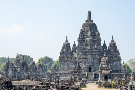 Ancient Sewu Buddhist temple stone ruins with ornate stupas under a clear blue sky in Klaten, Central Java, Indonesia on a bright sunny day.