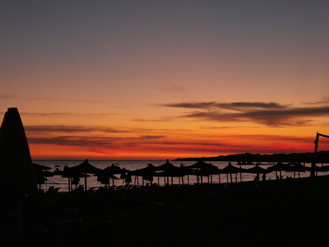Parasols et transats sur une plage au coucher du soleil