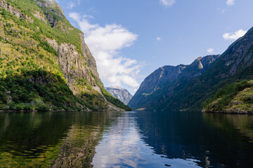 Fototapeta premium Tranquil Norwegian fjord landscape with steep green mountains and calm water reflections