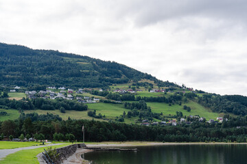 Obraz premium Scenic Norwegian village nestled on a green hillside overlooking a calm lake