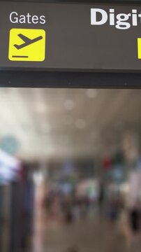 Airport sign indicating the direction to the gates and the digital border entry, with travelers walking in the blurred background. Biometric technology is improving security and streamlining travel