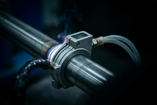 Close up of orbital welding head clamped on steel tube during automated pipe welding process