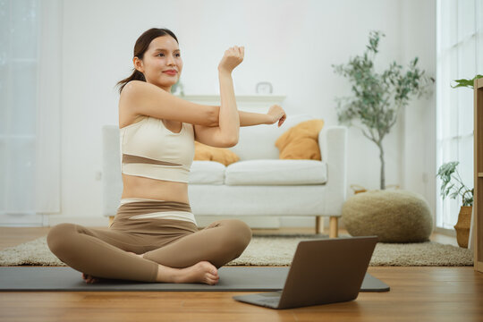 A seated adult stretches an arm across her chest as stretching and lifestyle help women seek living and wellbeing, then stretching and lifestyle help women sustain living and wellbeing near a screen.
