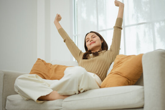 An adult stretches arms overhead as relaxed living links a livingroom to mindfulness and satisfaction, then relaxed living brings a livingroom towards mindfulness and satisfaction during the stretch.