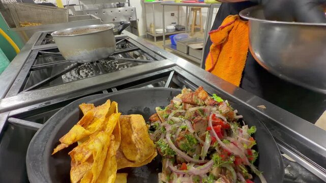 chef plating fried plantain chips beside bacon salad dish in kitchen
