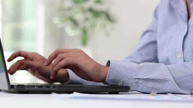 Businesswoman hands typing on a laptop keyboard during working hours in the office, concept of a professional employee answering emails and writing business documents