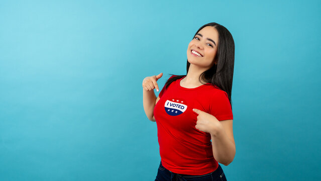 Young latina woman proudly presenting her i voted sticker after casting a ballot