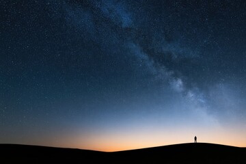 Obraz premium Lone figure silhouetted against a vast, star-filled night sky