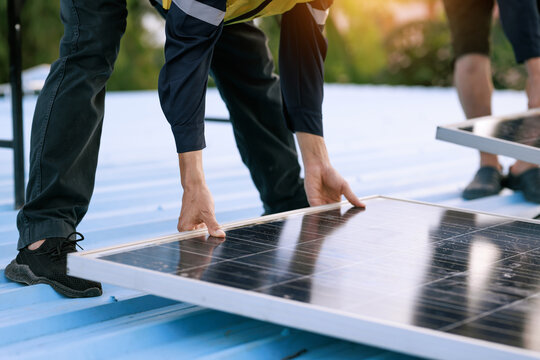 Technicians install a solar panel on a rooftop, clean energy work, renewable power, and modern sustainable construction.
