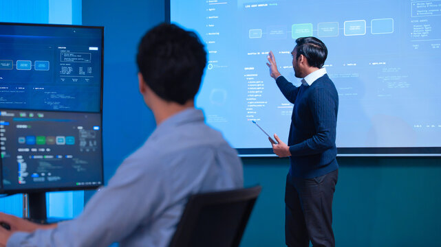 IT professional presenting system workflow and software code process to colleague in modern control room
