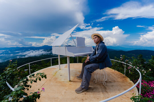 Side profile of Asian male tourist in hat looking at mountain view on skywalk near flower garden