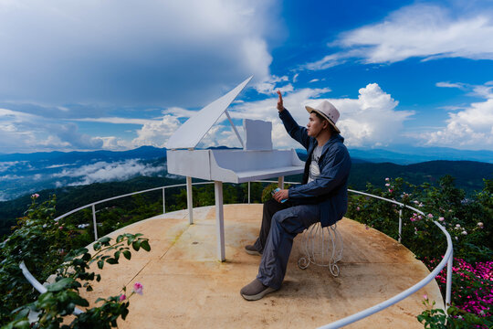 Side profile of Asian male tourist in hat looking at mountain view on skywalk near flower garden