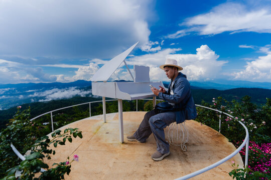 Side profile of Asian male tourist in hat looking at mountain view on skywalk near flower garden