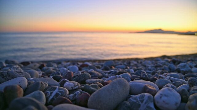 Pebble beach with gentle waves rolling toward shore at sunset