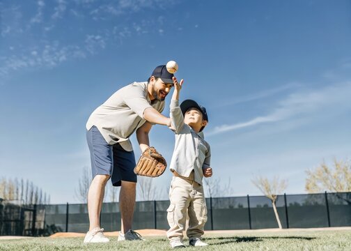 Father and son playing catch in a park