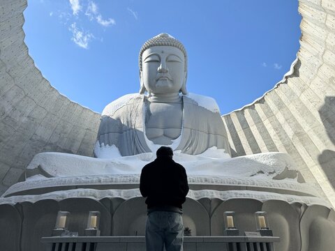 Tourist looking at the giant stone Buddha statue covered in snow at the Hill of the Buddha in Sapporo, Japan.