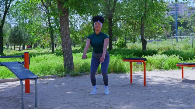 Fit african american woman performing squats in outdoor park